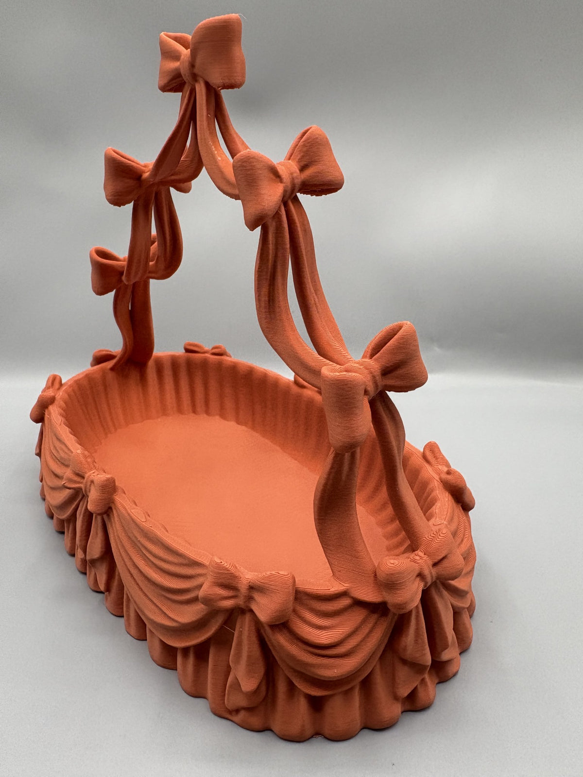 Coquette bow jewelry holder with an arched necklace stand over a scalloped catchall tray