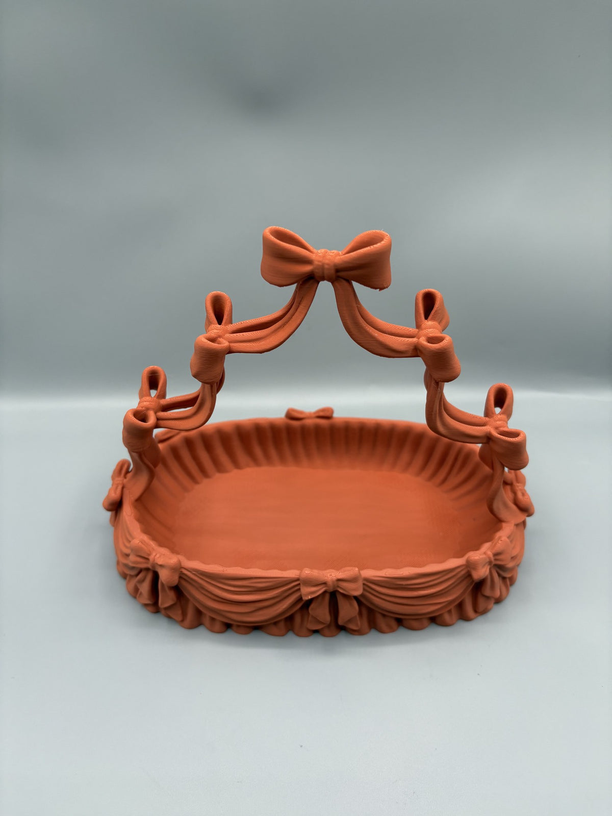 Coquette bow jewelry holder with an arched necklace stand over a scalloped catchall tray