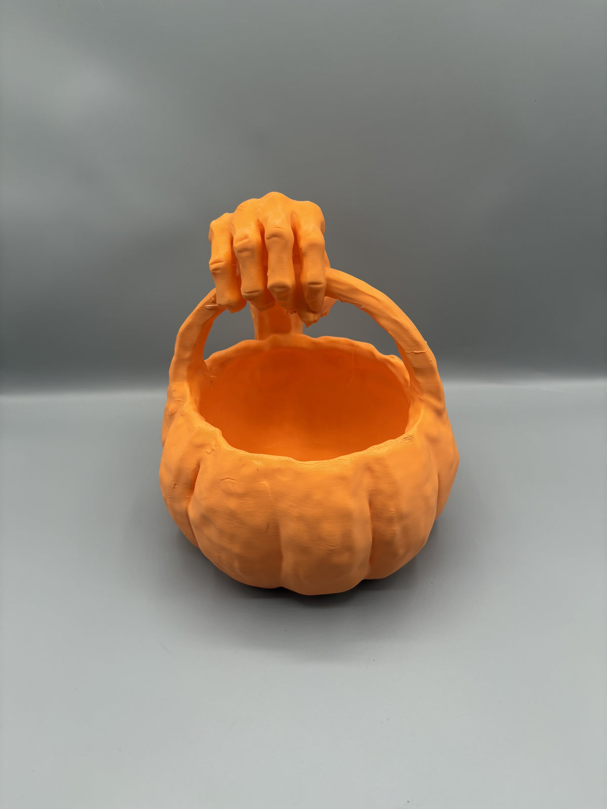 Orange monster hand pumpkin candy bowl, top view showing the open bowl and claw on the handle
