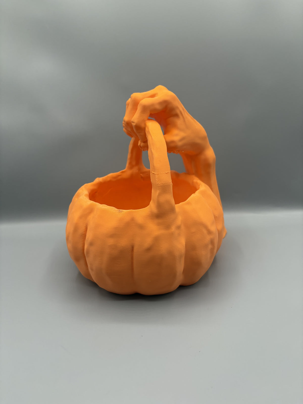 Orange monster hand pumpkin candy bowl, angled side view of the claw gripping the arched handle