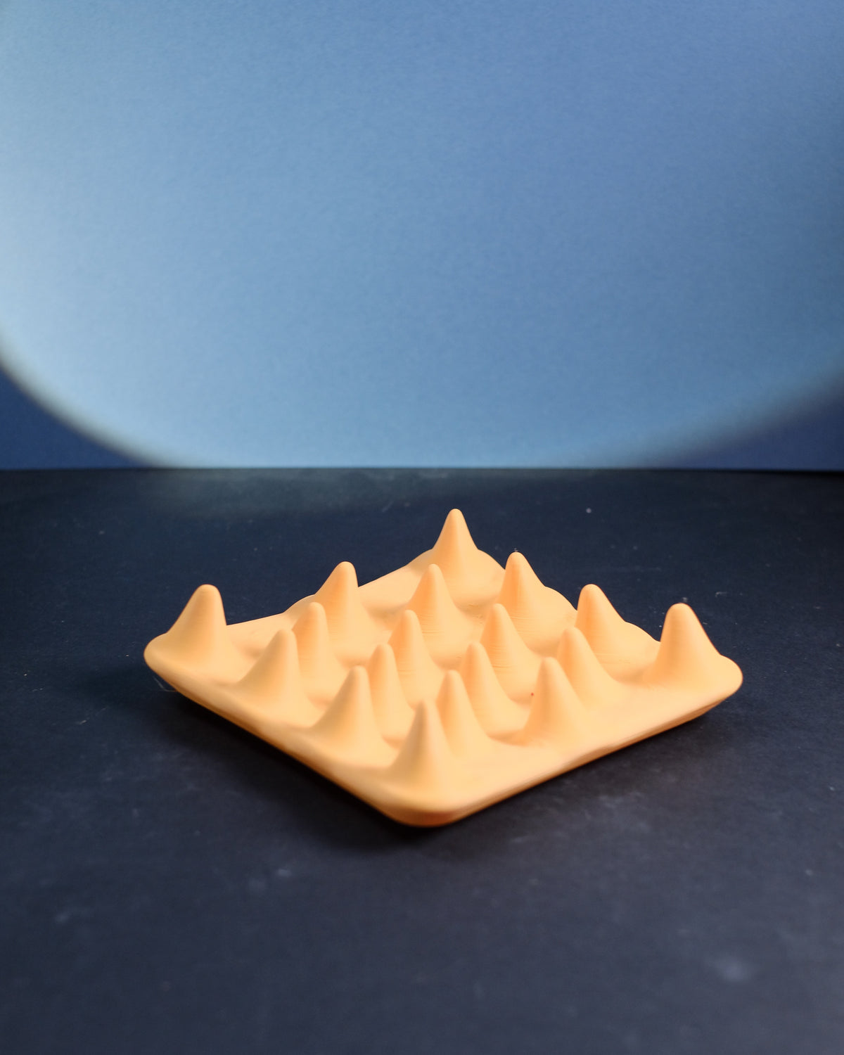 Modern spiked jewelry ring tray, angled studio view on a dark surface