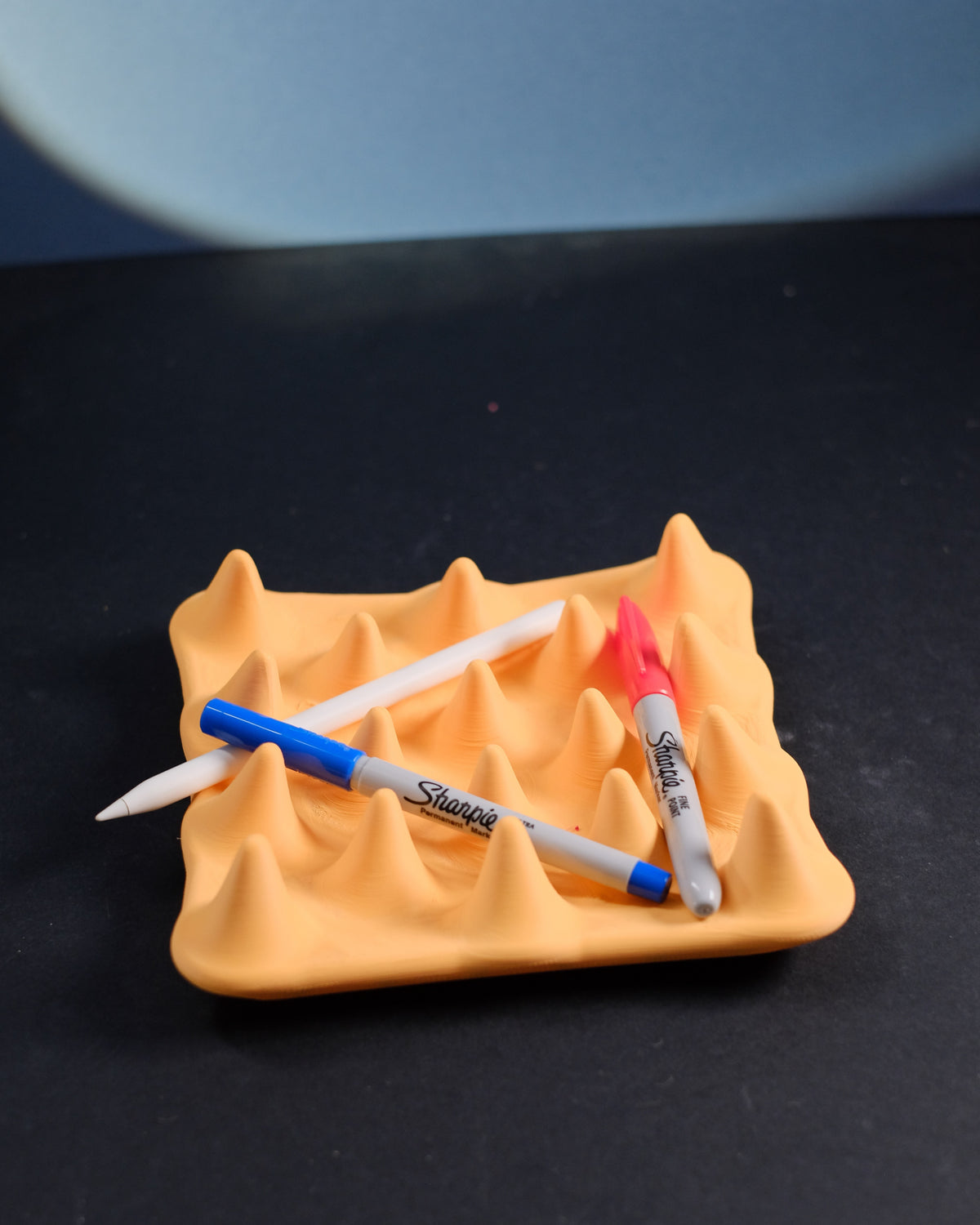 Spiked catch-all tray holding pens between the peaks
