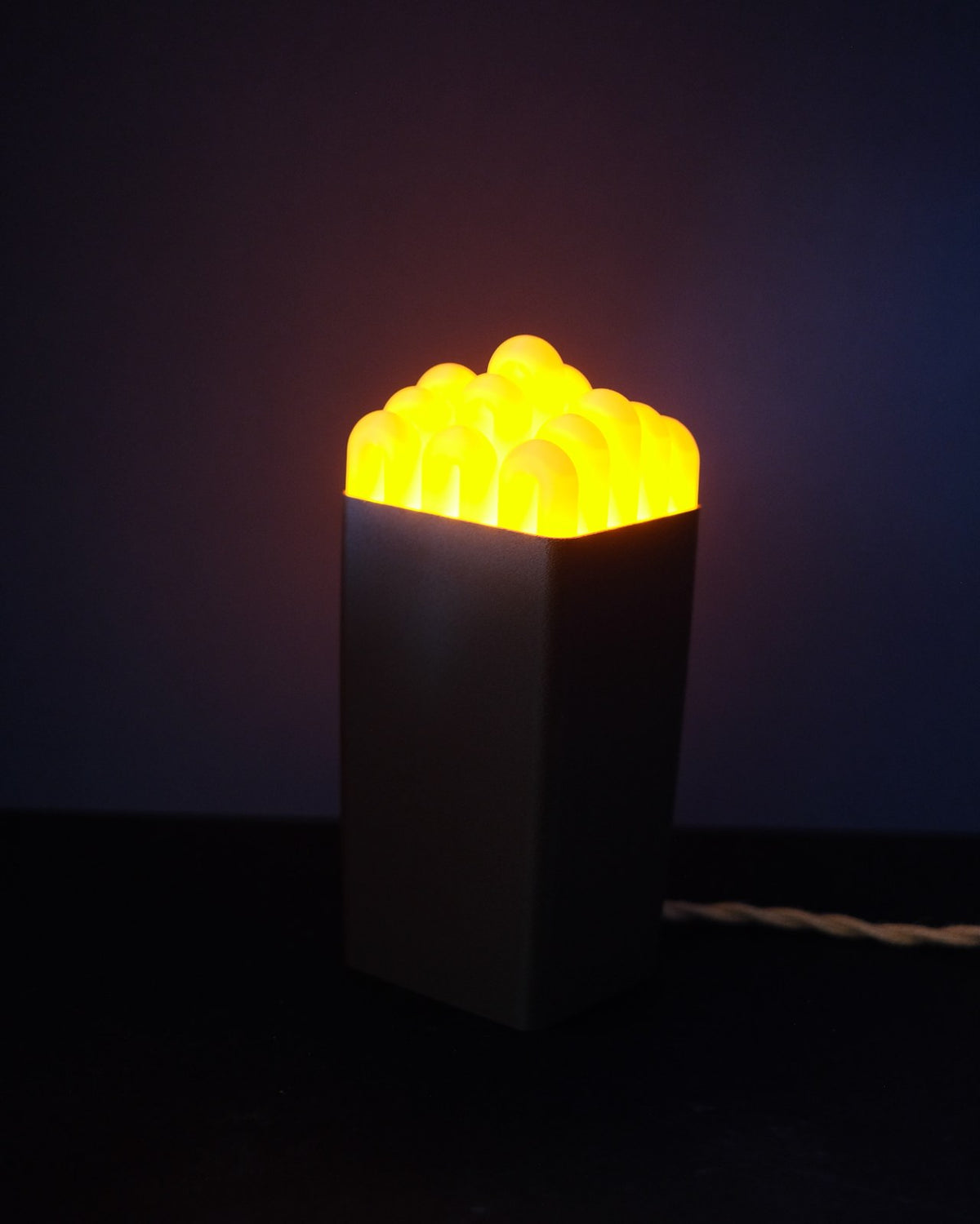 Funky wibble cap table lamp lit, warm glow through the arched yellow cap